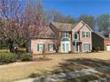 Charming two-story brick home with green shutters, complemented by a blooming tree at 1603 Pinder Point Dr, Lawrenceville, GA 30043