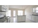 Kitchen boasting white cabinets, granite counters, an island, stainless appliances, and tile floors at 1056 Fern Valley Way, Dacula, GA 30019
