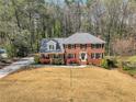 Two-story brick home featuring a well-manicured lawn and gray roof nestled within a wooded landscape at 1135 Parkview Sw Way, Lilburn, GA 30047