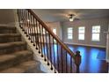 View of staircase featuring dark wood and iron spindles, carpeted steps, and an open view to the living room at 3718 Southfield Ct, Loganville, GA 30052