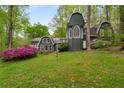Spacious backyard featuring lush greenery, a charming facade with arched windows, and blooming azaleas at 2977 Glover Dr, Cumming, GA 30040