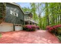 Paver driveway leading to a charming two-story home with white garage doors and mature trees at 2977 Glover Dr, Cumming, GA 30040