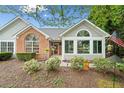 Inviting single-Gathering home showcasing a brick facade, sunroom, and manicured landscaping at 12103 Windrush Ln, Alpharetta, GA 30009