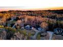 An aerial view of a home surrounded by woods in a rural neighborhood with sunset in the background at 114 Hardwood Ln, Canton, GA 30115