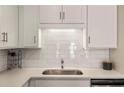 Close-up of a modern kitchen with white cabinets, a stainless steel sink, and a subway tile backsplash at 2030 Main Nw St # 207, Atlanta, GA 30318