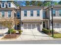 Charming townhome featuring a modern brick exterior, a two-car garage, and manicured landscaping at 5018 Towneship Creek Rd, Roswell, GA 30075