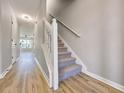 Hallway with hardwood flooring leading to a staircase and a living area with a fan at 7229 Georges Way, Morrow, GA 30260