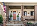 Inviting front porch with stone stairs, decorative lanterns, sunburst decor, and lush ferns, creating a warm welcome at 561 S Club Dr, Woodstock, GA 30188