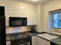 Functional kitchen featuring white cabinets and black appliances, including a microwave and stove at 300 Peachtree Ne St # 9A, Atlanta, GA 30308