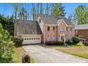 Two-story brick home with an attached two-car garage, driveway, and landscaped front yard with mature trees at 6317 Southland Forest Dr, Stone Mountain, GA 30087