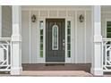 A close-up of the front door with decorative glass, sidelights, and classic lantern-style sconces at 100 Oakwind Pkwy, Canton, GA 30114