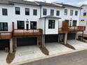 Modern townhome exterior showing garage access beneath a deck, completed with black garage doors and brick siding at 634 Skytop Dr # 155, Cumming, GA 30040