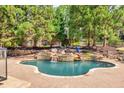 Relaxing backyard pool with waterfall feature, surrounded by lush greenery at 2335 Flat Stone Dr, Cumming, GA 30041