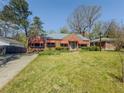 Charming brick home featuring a well-manicured lawn, mature trees, and red awnings at 1368 Scott Blvd, Decatur, GA 30030