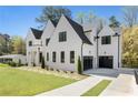 Elegant white brick home with black trim, a well-manicured lawn, and a spacious driveway leading to attached garages at 312 Meadow Dr, Alpharetta, GA 30009