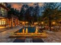 Backyard pool area at dusk, featuring a fire pit, lounge chairs, and beautifully lit landscaping at 2461 Oak Grove Ne Ests, Atlanta, GA 30345