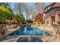 Large pool and stone patio surrounded by a green lawn and mature trees at 2461 Oak Grove Ne Ests, Atlanta, GA 30345