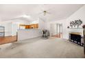 Spacious living room featuring neutral carpet, white walls, a fireplace, and an open view to the kitchen at 57 Sorghum Ct, Dallas, GA 30157