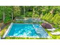 Aerial view of a backyard oasis with a pool, jacuzzi, and tennis court surrounded by lush greenery at 891 Glenbrook Nw Dr, Atlanta, GA 30318