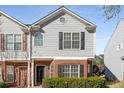 Close-up of a brick and grey sided townhome featuring a black front door and manicured bushes at 4917 Walden Lake Sq, Decatur, GA 30035