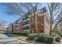 Exterior of The Richmond Condominiums featuring brick facade, balconies, and mature trees at 2921 Lenox Ne Rd # 113, Atlanta, GA 30324