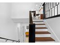 Bright staircase with white walls, wood steps, and a sleek black railing leading to the open kitchen at 6660 Hidden Brook Trl, Atlanta, GA 30349