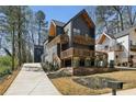Contemporary two-story home showcasing a dark exterior, stylish wooden balconies, and a concrete driveway at 1792 Charles Nw Pl, Atlanta, GA 30318