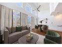 This airy living room features high ceilings, a ceiling fan, and natural light from large windows with cream-colored curtains at 1221 Caroline Ne St # 201, Atlanta, GA 30307