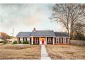 Charming brick home featuring a red front door, black shutters and inviting front porch at 3874 Carriage Sw Ln, Conyers, GA 30094