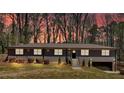 Dusk view of the home featuring a brick facade, mature landscaping, and an attached garage at 3819 Dora Se Dr, Smyrna, GA 30082