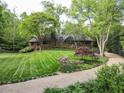 Stone cottage-style home with manicured lawn, gravel drive, and mature trees providing privacy at 1050 E Club Ne Ln, Atlanta, GA 30319