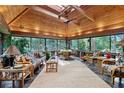 Bright sun room with wood ceiling, ceiling fan, stone accents and walls of windows with wooded views at 1050 E Club Ne Ln, Atlanta, GA 30319