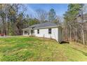 A single-story white home with a convenient carport on a well-manicured lot surrounded by trees at 2374 Buchanan Hwy, Dallas, GA 30157