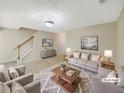 Bright, neutrally decorated living room with a large window, stairs, and cozy seating at 1005 Magnolia Gardens Walk, Mcdonough, GA 30253