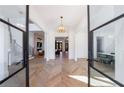 Sunlit foyer with herringbone wood floors, glass front doors, and designer chandelier at 835 Kenry Ct, Atlanta, GA 30342