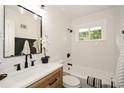 Bright bathroom featuring white herringbone tiles, black fixtures, and a wood-finish vanity at 1048 Pinehurst Se Dr, Smyrna, GA 30080