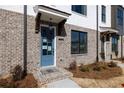 Townhome showcasing a blue door, brick exterior, small porch, and neatly arranged landscaping at 1132 Larkin Dr # 34, Buford, GA 30518