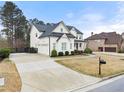 Beautiful white home featuring a three-car garage and well-maintained front yard at 6635 Canyon Cv, Cumming, GA 30028