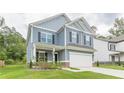 Charming two-story home with a covered porch, a two-car garage, blue siding, and manicured lawn, creating curb appeal at 9061 Jim Purcell Dr, Covington, GA 30014