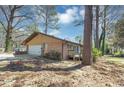 View of the rear exterior, showing a small deck and grassy yard with mature trees at 5415 Orly Ter, Atlanta, GA 30349