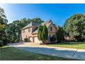 Beautiful brick home featuring an attached two-car garage, well-manicured lawn, and mature trees at 5347 Harbury Cv, Suwanee, GA 30024