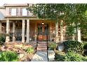 Inviting covered front porch with brick columns, double doors, and elegant landscaping at 5347 Harbury Cv, Suwanee, GA 30024