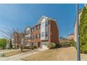 Exterior view of a brick townhome featuring an attached garage and a well-maintained lawn on a bright, sunny day at 2164 Mill Garden Run, Buford, GA 30519