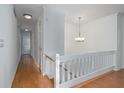 Bright hallway with hardwood floors, white walls, a staircase with white railings, and modern lighting fixtures at 5030 Sumit Wood Dr, Kennesaw, GA 30152