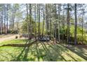 Expansive backyard with mature trees, a trampoline, and a cozy fire pit area at 6065 Nw Gentlewind Court Nw Ct, Powder Springs, GA 30127