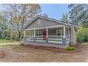 Inviting single-story house featuring a covered front porch and mature trees at 1248 W Ridge Ave, Stone Mountain, GA 30083