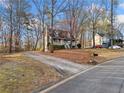 A charming home boasts a spacious driveway and lush, mature landscaping at 9061 Greenwood Way, Canton, GA 30115
