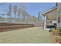 A spacious backyard featuring a wood fence, grassy area, and a covered patio for outdoor enjoyment at 516 Cunninghame Ct, Peachtree City, GA 30269