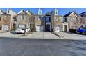 A view of several brick townhomes, each with a one car garage and blue skies above at 1749 Coleville Oak Ln, Lawrenceville, GA 30046