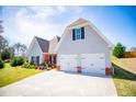 Two-car garage with brick accents, a wide driveway, and green lawn at 207 Meadow Lake Dr, Carrollton, GA 30116